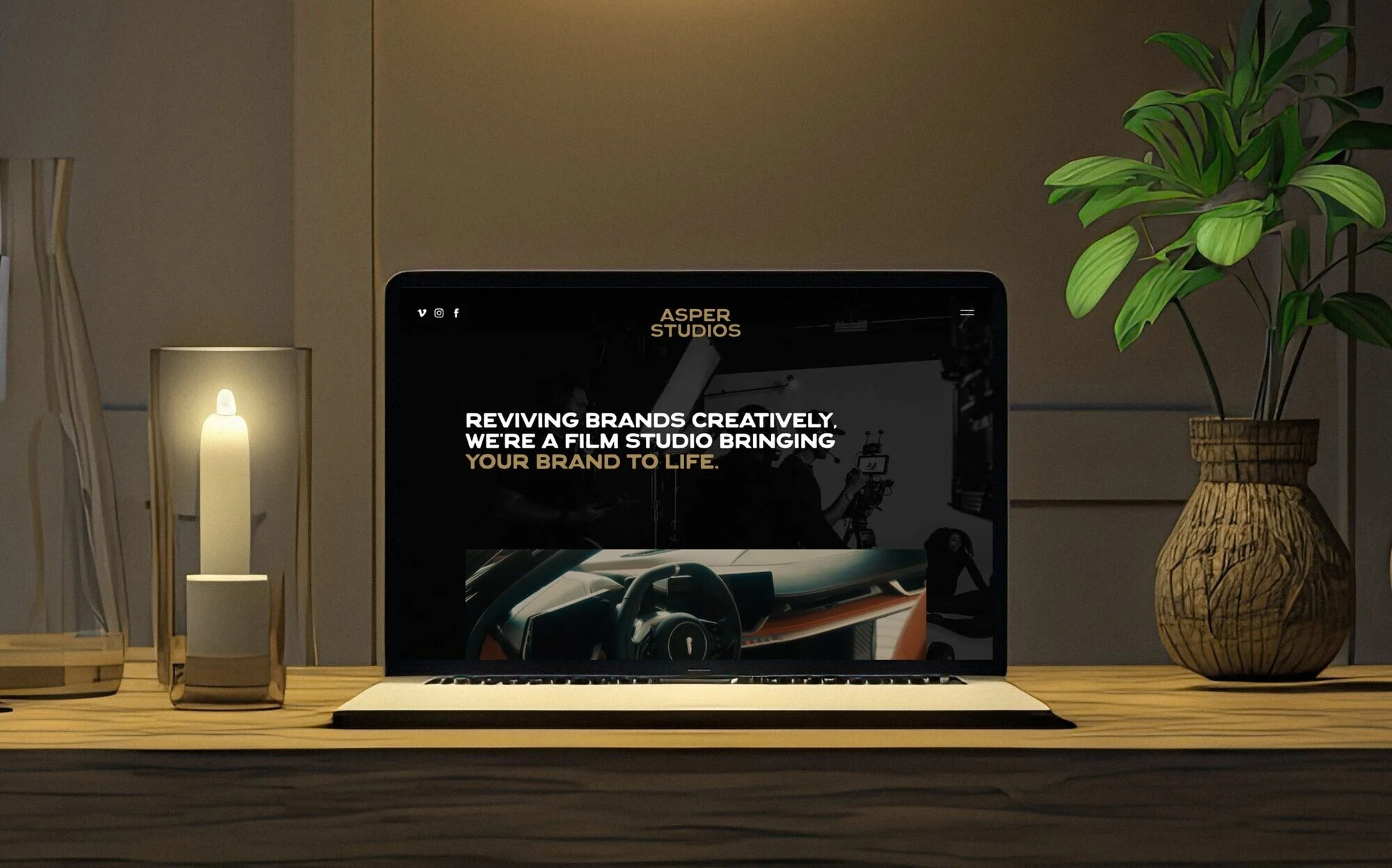 The Asper Studios website on a laptop beside a candle