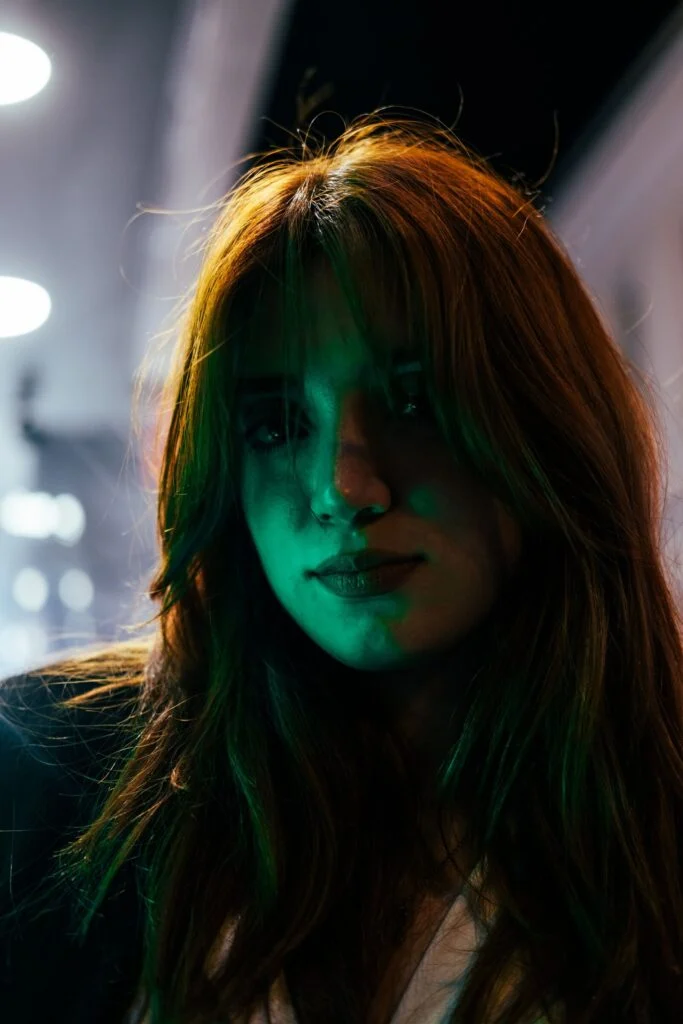 Portrait of a woman with long red hair in soft green light