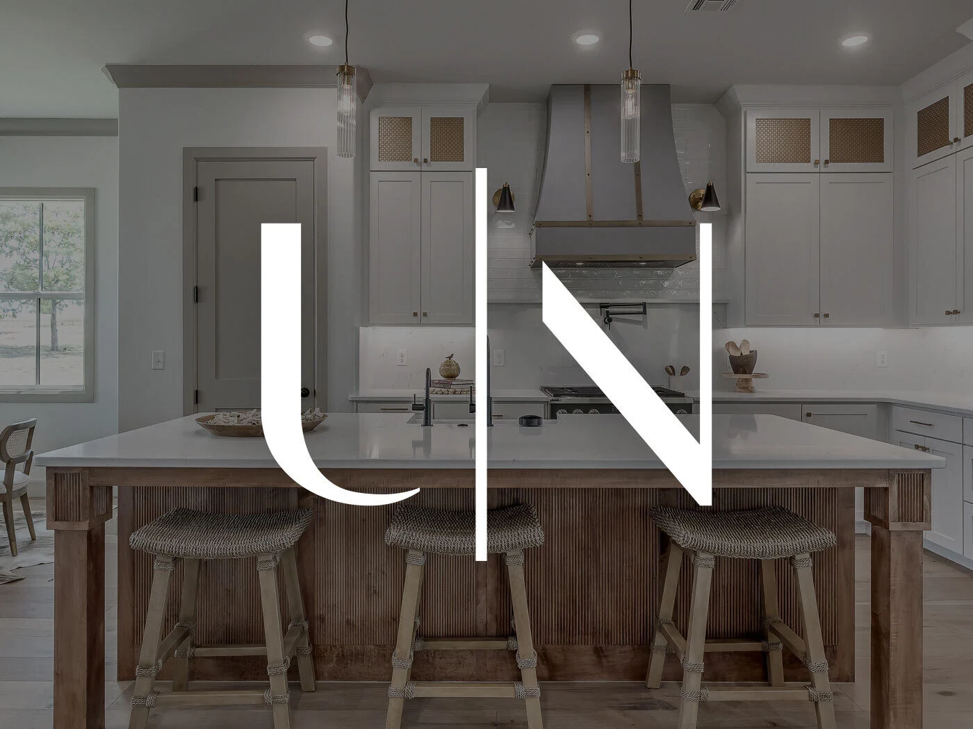 Urban Nest Homes logo over a custom kitchen with a wood island